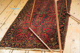 Vintage Sarouk rug with dark navy border, cherry red floral field, and worn fringe.