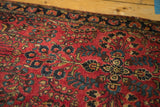 Dark cherry red field and intricate navy blue floral vinery of a Sarouk rug.