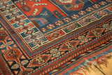 Geometric borders of an antique Kamseh rug in madder red, indigo blue, and green, with tattered ends.
