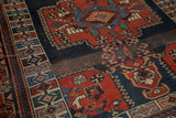 Aged texture and intricate geometric border patterns in madder red and navy on an antique Kamseh rug.