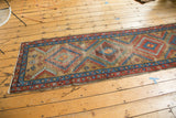 Vintage Bakshaish runner showing concentric diamond motifs, serrated relief, in camel, red, and blue.