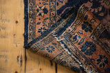 Folded antique Lilihan rug runner showing navy blue indigo ground and terra cotta floral patterns.
