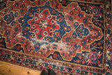Distressed Vintage Baktiari rug showing navy medallion, red field, and worn foundation.