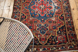 Decorative red rust, navy blue Baktiari rug with geometric motifs and distressed texture.