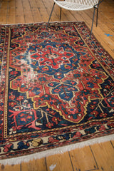 Detail of vintage Baktiari rug with distressed navy field, red border, and white fringe.