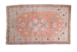 Antique Khotan carpet with distressed terra cotta medallion and vibrant pink floral motifs.