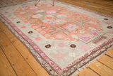 Corner of antique Khotan carpet, revealing pink geometric border and distressed ivory field.