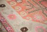 Antique Khotan rug section featuring upbeat terra cotta and pink floral motifs, beige border.