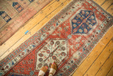 Antique North West Persian runner features red field, blue hexagonal medallion, floral motifs, varied pile.