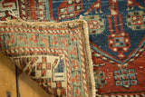 Antique North West Persian runner: hand-knotted back, tattered side, and navy, red geometric pattern.