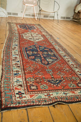 North West Persian antique rug's geometric border, madder red field, aged pile, and side tatter.