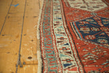 Angled detail of antique Persian runner's madder red field, geometric border, and side tatter.