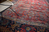 Worn cherry red floral field and navy blue border of a vintage Mahal carpet.