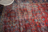 Distressed vintage Mahal carpet texture with faded floral designs and cherry red ground.