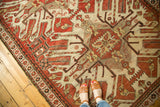 Geometric rust and ivory pattern of a vintage Kazak rug with feet in sandals.