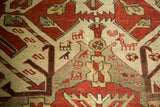 Intricate geometric motifs with stylized serpents, goats, and birds on a vintage Kazak carpet.