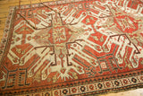 Close-up of vintage Kazak rug: rust, ivory geometric medallion, abstract animal motifs.