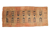 Antique Caucasian runner rug with navy geometric medallions, crab motifs, sand field, blush border.