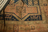 Stylized animal figures within navy and blush geometric patterns of an antique Caucasian rug.