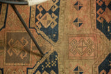 Antique hand-knotted geometric motifs in navy, blush, and sand, with visible pile wear.
