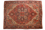Vintage Heriz carpet with ruby red field, navy blue borders, central medallion, and arabesque spandrels.