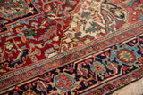 Detailed corner of a vintage Heriz carpet with ruby red, navy blue, and arabesque spandrels.