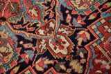 Ruby red, navy, and cream arabesques on vintage Heriz carpet, with visible pile wear.