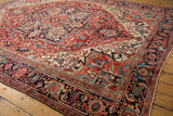 Corner of vintage Heriz carpet, displaying ruby red field, rich navy border, and unique arabesques.