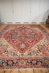Close-up of Heriz carpet's secured fringe, showcasing navy, ruby red, and blush geometric motifs.