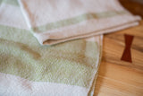 Handwoven lime and cream striped dish towel, showing textured weave detail.