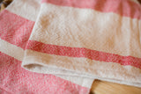 Folded detail of the handwoven red and natural white striped cotton towel.