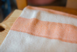 Handwoven Loomination dish towel showing the textured weave of tangerine orange and white stripes.