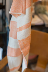 Close-up showing the handwoven texture of a tangerine orange and white striped dish towel.
