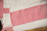 Visible hand-woven texture of scarlet red and cream striped cotton throw.