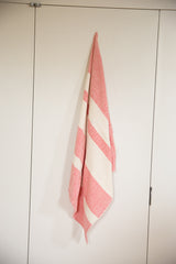 Handwoven spa towel in scarlet red and cream stripes hanging to show its soft fabric.
