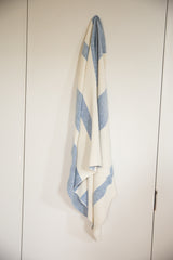Hand-woven cotton spa towel, draped vertically with blue and cream wide stripes.