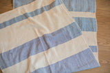 Hand-woven cotton spa towel with textured blue and cream ticking stripe pattern.