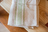 Handwoven lime and cream cotton napkins with visible textured weave and natural twine tie.