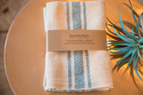 Handwoven Loomination teal blue and cream striped cotton napkins with brand band.