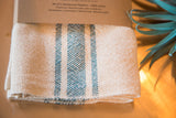 Handwoven napkin showing textured cream and teal blue striped pattern.