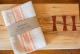 Handwoven Loomination tangerine and cream striped napkin set.