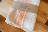 Loomination handwoven tangerine striped cotton napkin set, with visible woven texture.