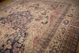 Low pile of an antique Kermanshah showing the navy medallion beside a sand field with cochineal red vinery.
