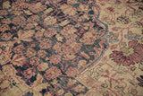 Close-up view of the antique Kermanshah's low pile, showing knot heads and floral vinery detail.