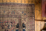 Overhead view of an antique Kermanshah's detailed floral borders and time-softened, worn pile.