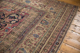 Corner of an antique Kermanshah rug showing intricate floral borders and wear to the knot heads.