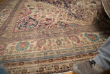 Antique Kermanshah carpet's low pile showing visible knot heads and intricate floral border design.