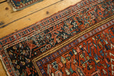 Karaja rug's finely woven geometric border details in brick red, dark teal, and blue tones.