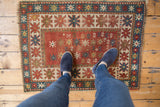 Feet on antique Kazak rug, highlighting playful abstract animals and starburst border motifs.