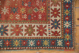 Antique Caucasian Kazak rug corner with geometric starburst borders in terra cotta, blue, cream.